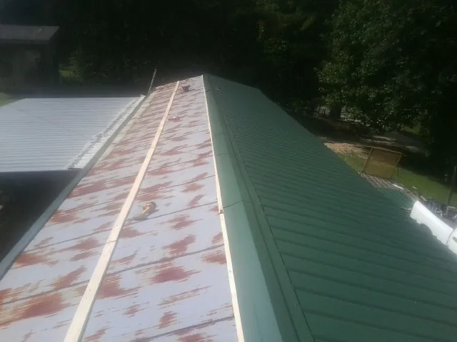 Old rusted panels beside newly installed green metal roofing — Wind Damage Roof Repair by Roofing Brothers in Tenmile