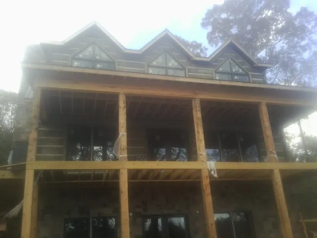 Dormers and porch framing on a large log home under construction — Roof Coating work by our crew in Tenmile