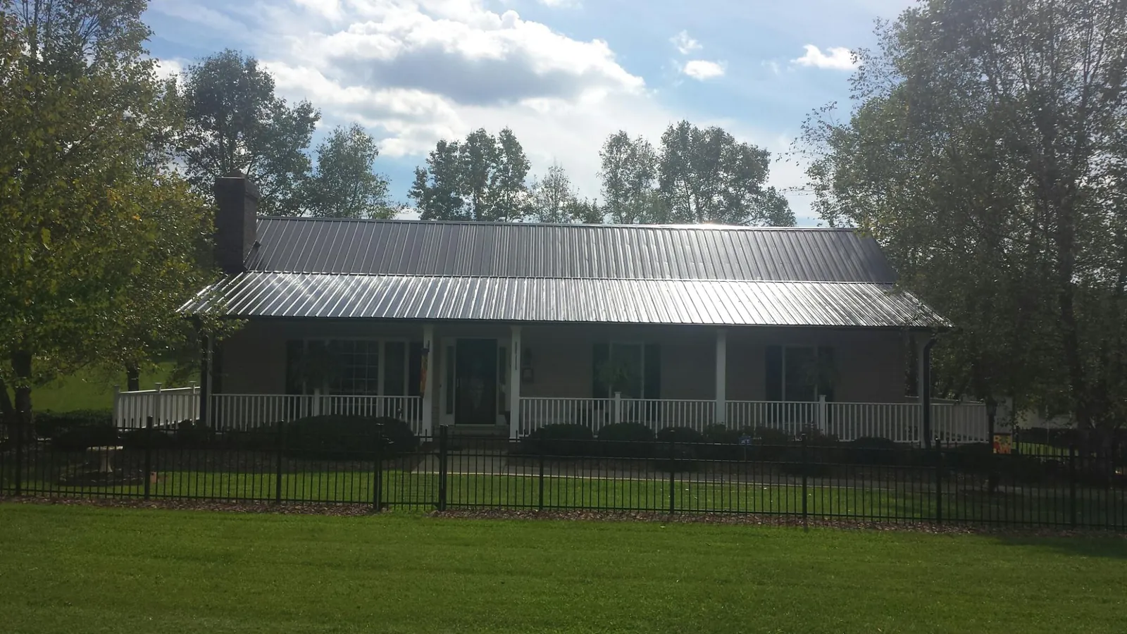 Gray metal roof on a brick ranch with a full width front porch — Gutter Guard Installation work by our crew in Tenmile