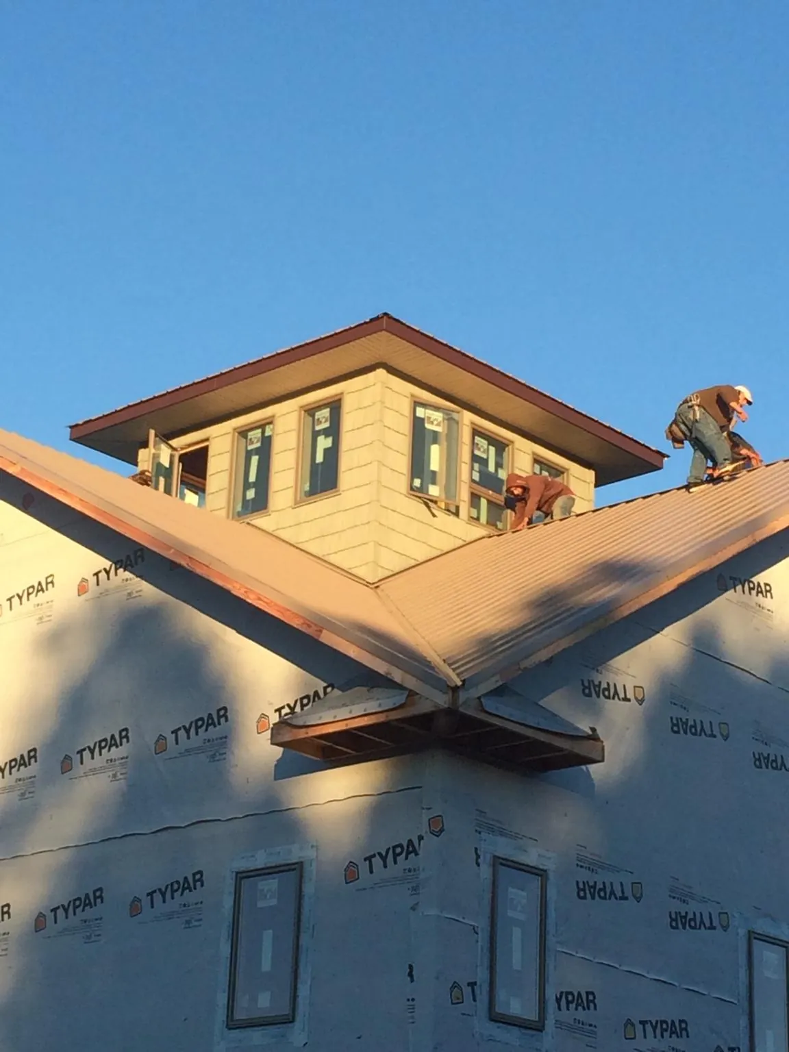 Roofers working around a rooftop cupola on a new metal roof at sunset — Roof Waterproofing in Tenmile by Roofing Brothers